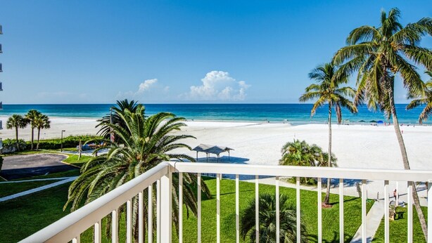 A beach view from a balcony with palm trees and a clear sky. - Prime Beachfront with Views Views Views! (Siesta Key)