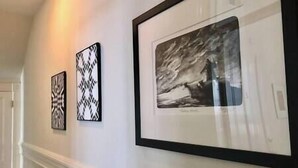 Een hal met drie kunstwerken in lijsten aan de muur.