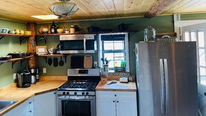 Une cuisine compacte avec des poutres en bois au plafond, une cuisinière, un four à micro-ondes et un réfrigérateur.