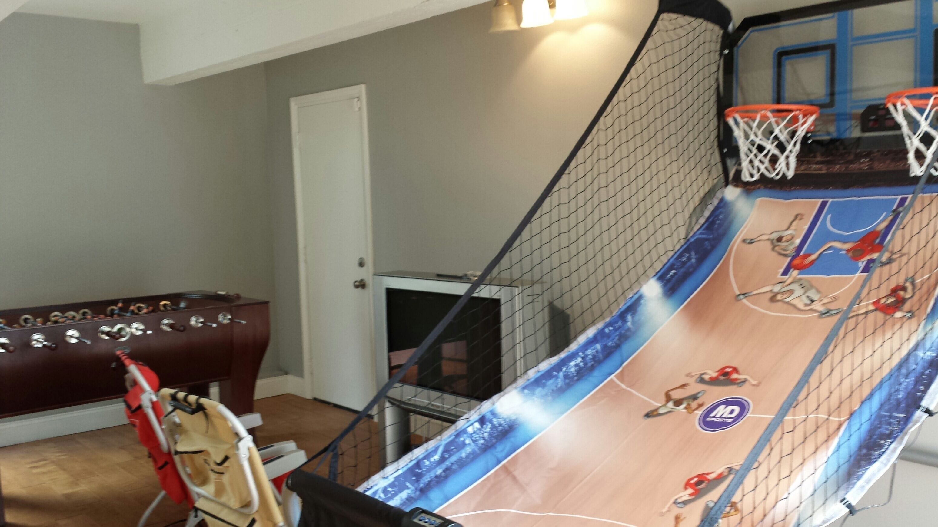 Un terrain de basket-ball installé à la maison, avec un panier, une porte et un meuble en bois.
