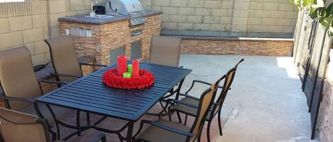 An outdoor patio with a table and chairs, a barbecue grill, and a decorative centerpiece.