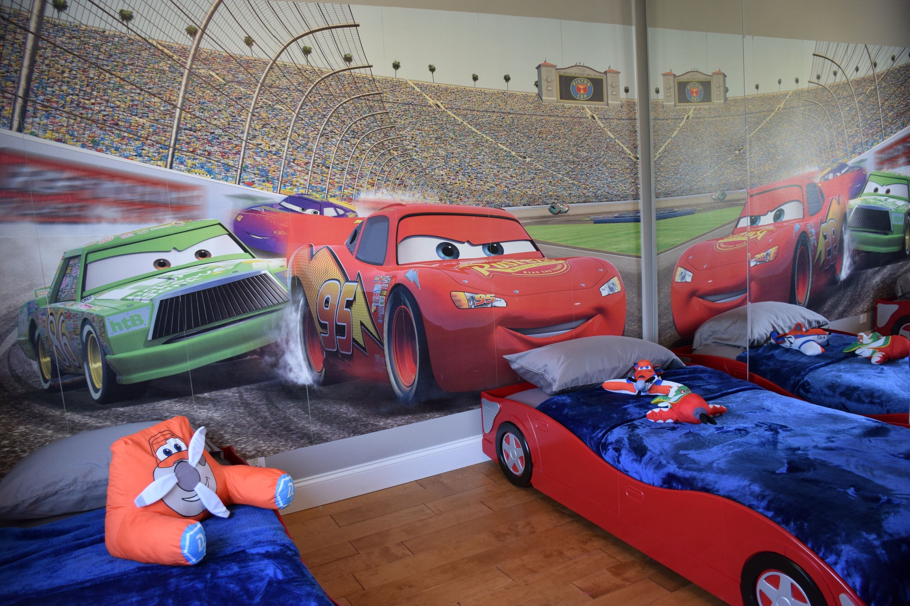 A children's bedroom with a race car theme, including a mural, themed bedding, and a toy car.
