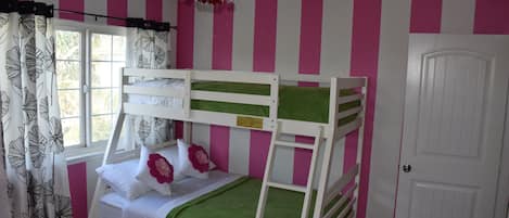A bunk bed room with pink and white striped walls, a white door, and a window with curtains.