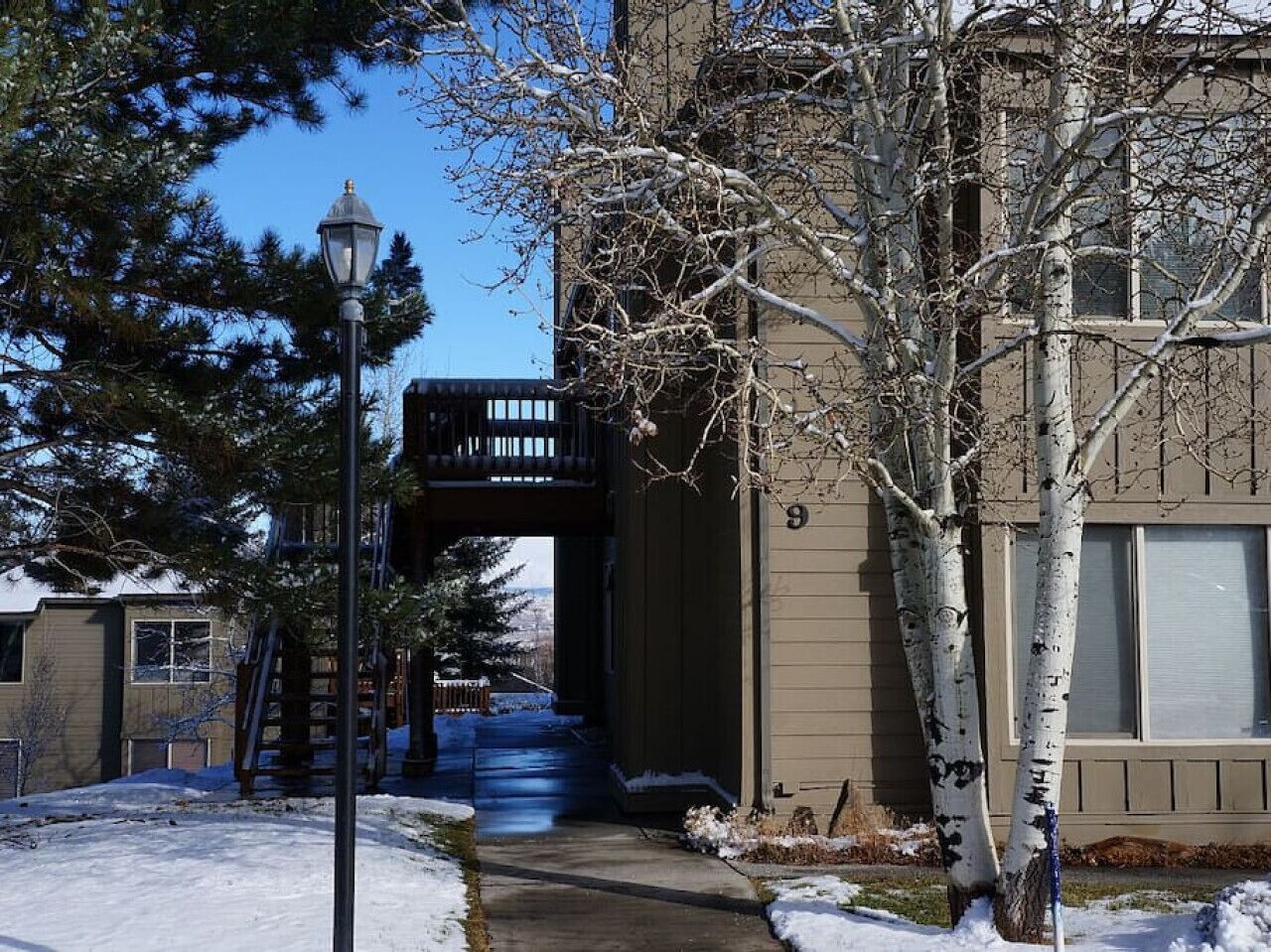 A building with a covered walkway, a street lamp, and snow on the ground.