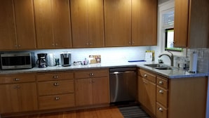 Una cocina con armarios de madera, lavavajillas de acero inoxidable, microondas y cafetera.