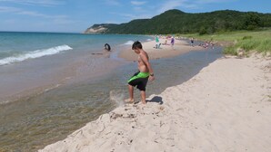 A beach with clear water, sandy shore, and people enjoying the beach.