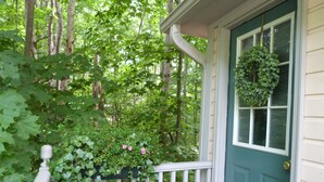 A house with a green door, a white porch railing, and a window with a wreath.