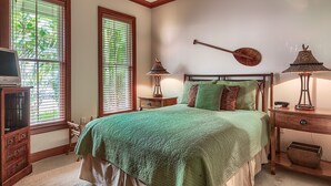 Un dormitorio con una cama, dos mesitas de noche, un cabecero de madera y un ventilador de techo.