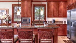 Una cocina con gabinetes de madera, un refrigerador de acero inoxidable, un microondas y una isla grande con taburetes de bar.