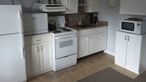 A kitchen with white cabinets, a stove, a microwave, and a kettle. - Quiet, clean, and comfy: Centrally Located In The Mt. Washington Valley. (Intervale)