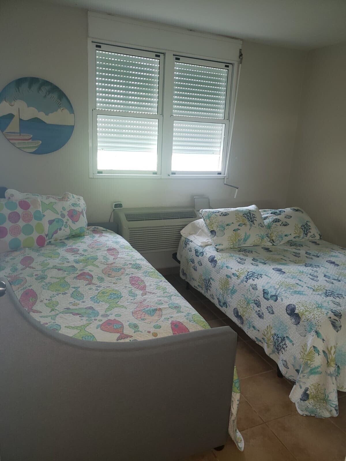A bedroom with two single beds, a radiator, and a window with blinds.