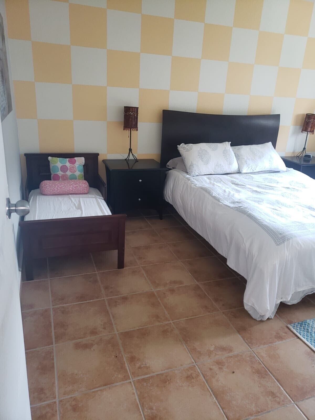 Una camera da letto con due letti, una parete a scacchi e pavimento piastrellato.