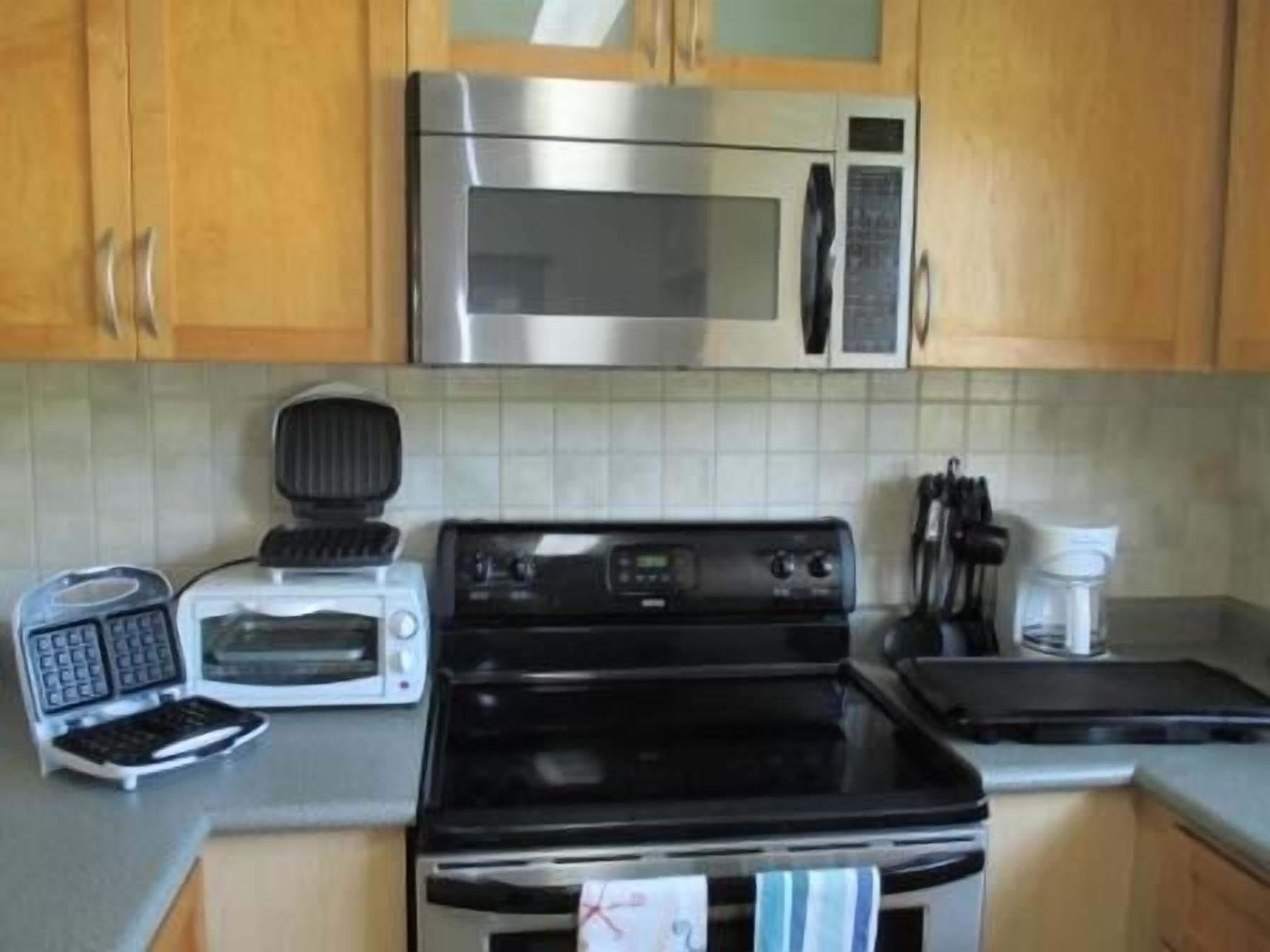 Una cocina con microondas, tostadora y estufa.