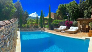 A swimming pool with lounge chairs and a stone wall.