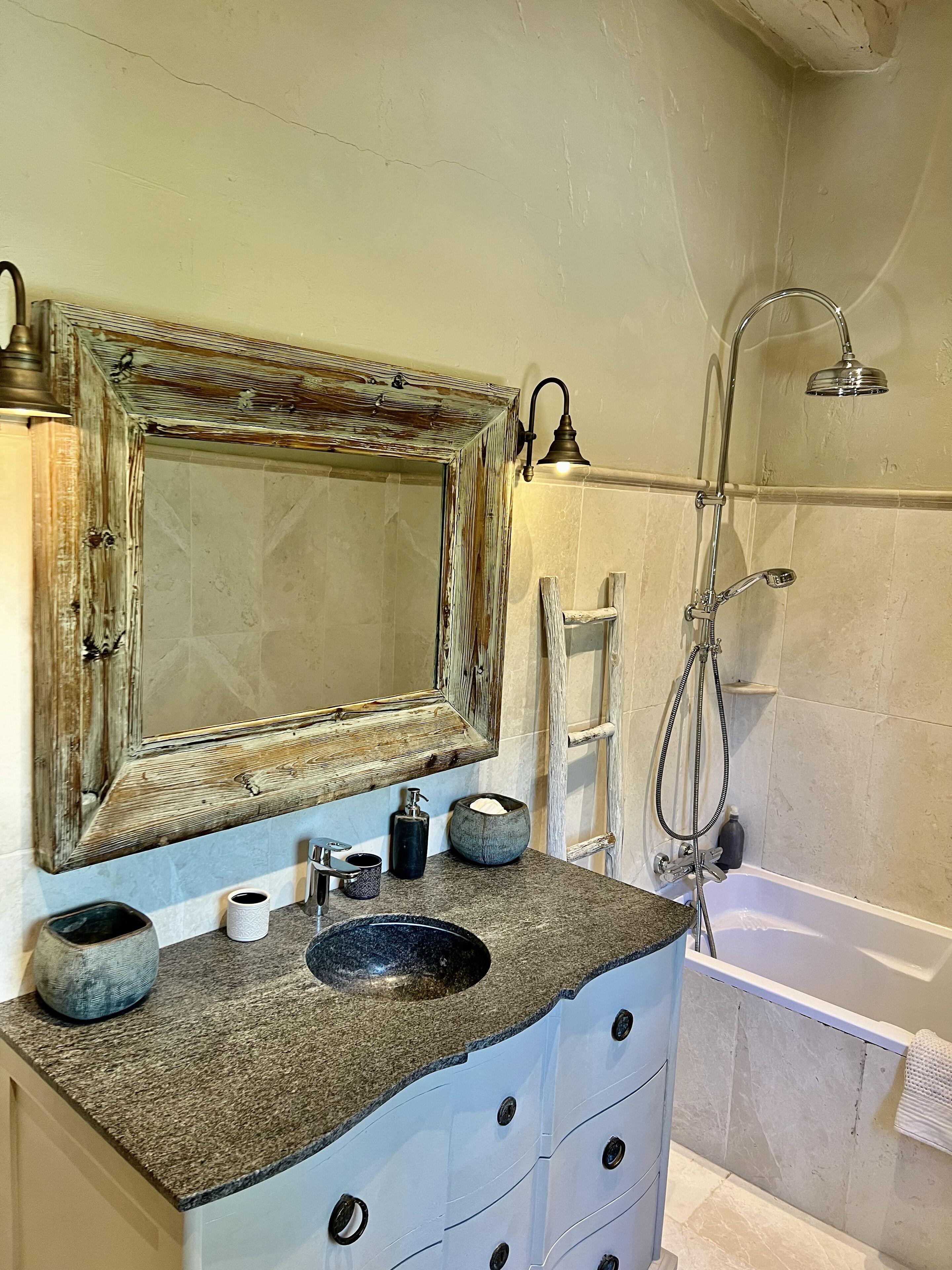A bathroom with a granite countertop, a large mirror, a shower, and a bathtub.