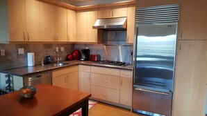A modern kitchen with stainless steel appliances, wooden cabinets, and a granite countertop. - Cool Downtown Orenco Loft (Hillsboro)