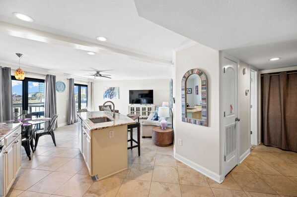 A spacious living area with a kitchen, dining area, and a large mirror.