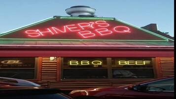 En restaurang med en neonreklamskylt där det står ”Shiner’s BBQ” och ”BBQ Beef” på fönstren.