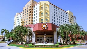Ein mehrstöckiges Hotel mit markantem Eingang, einer Statue davor und Palmen ringsherum.