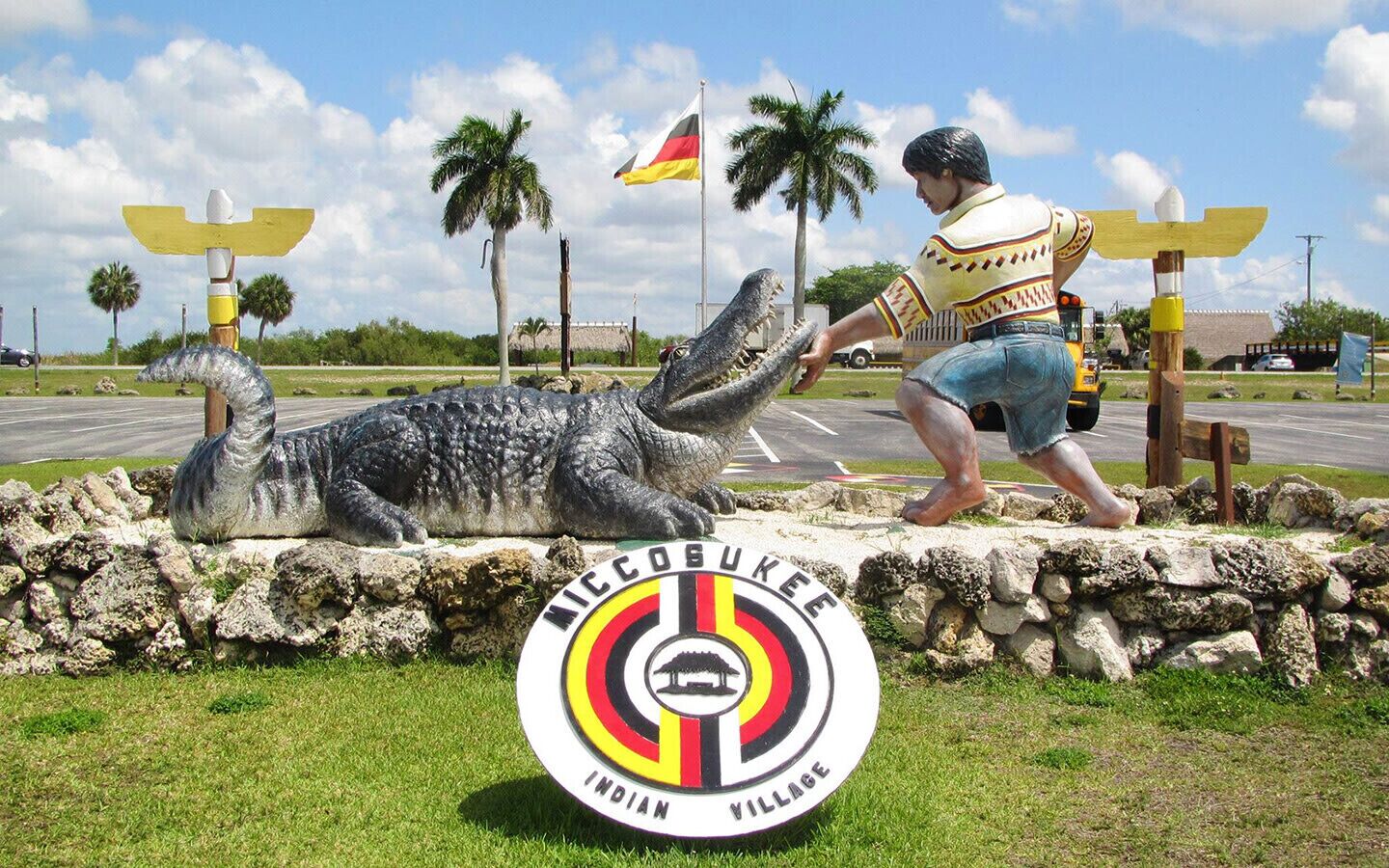 A statue of a man and a crocodile with a sign reading 'MICCOBUKEE INDIAN VILLAGE' in front.