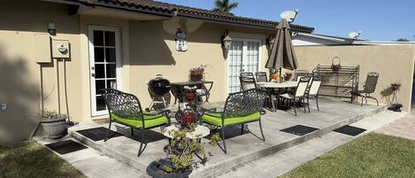Une terrasse avec des meubles d’extérieur, un barbecue et des plantes en pot.
