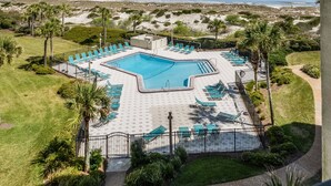 An aerial view of a resort with a swimming pool surrounded by lounge chairs and palm trees, overlooking a beach. - Beautiful Oceanfront Condo With Breathtaking Beach Views , 3RD floor, C117 (Fernandina Beach)