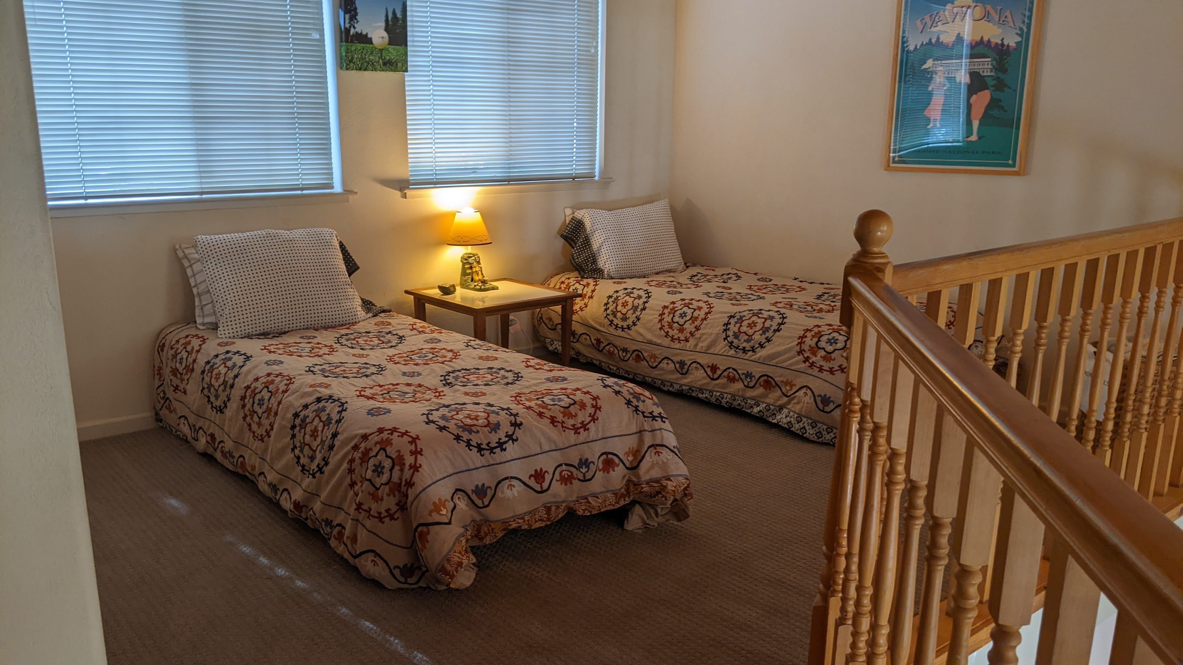 Ein Schlafzimmer mit zwei Betten, einem Nachttisch, einer Lampe und einem gerahmten Bild an der Wand.