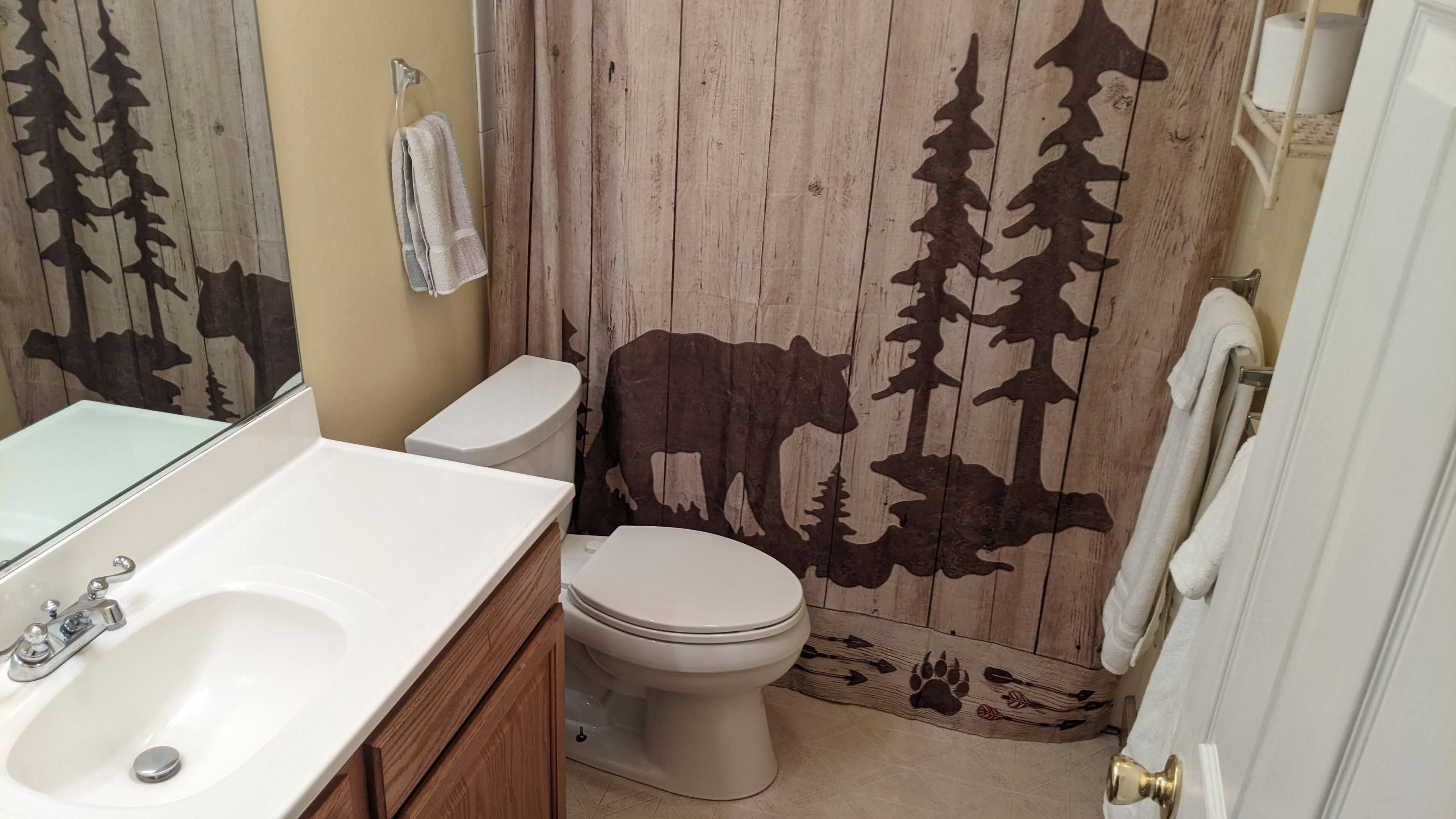 Un bagno con parete in legno, un water, un lavabo con specchio e un porta asciugamani.