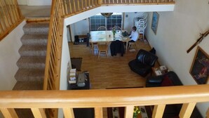 Un vaste espace de vie agrémenté d’un escalier en bois, d’une table à manger avec des chaises et d’un canapé en cuir noir.