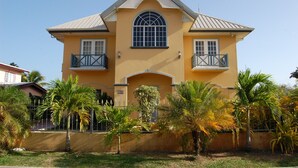A two-story house with a central arched window, two balconies, and a small front porch.