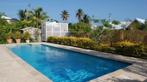 A rectangular swimming pool with clear blue water, surrounded by a tiled deck.