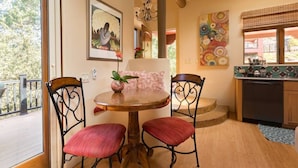 A dining area with a round table and two chairs, a chandelier, and artwork on the walls.