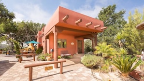 A rustic building with a patio area, outdoor seating, and a variety of plants.