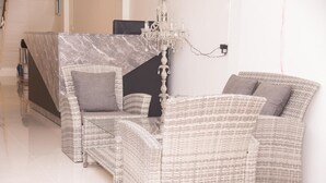 A modern living room with wicker furniture, a marble table, and a chandelier. - Nina Guesthouse (Bangkok)