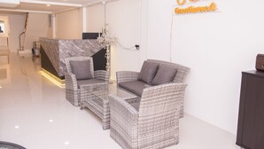 A modern interior with wicker furniture, a chandelier, and a sign reading "Nina Guesthouse." - Nina Guesthouse (Bangkok)