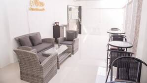 A modern guesthouse with wicker furniture, a glass-top table, and a ceiling fan. - Nina Guesthouse (Bangkok)