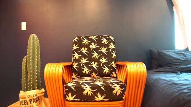A chair with a black seat and yellow leaf pattern, orange armrests, and a cactus decoration on a table. - Trip Spot 774 (Naha)