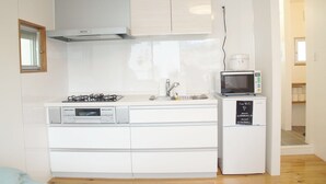 A compact kitchen with a gas stove, microwave, and built-in oven. - Trip Spot 774 (Naha)