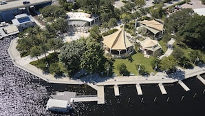 Luchtbeeld van een pand aan het water met een jachthaven, palmbomen en een centraal gelegen paviljoen.