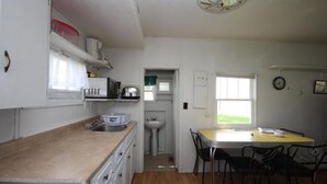 Una cocina compacta con lavamanos, microondas y comedor con mesa y sillas.
