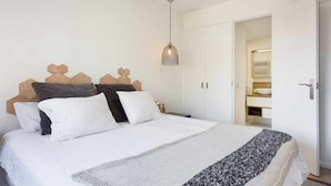 A bedroom with a bed, a hanging light fixture, a wardrobe, and a bathroom visible through an open door. - Sitges Colonial - Downtown near the Beach (Sitges)