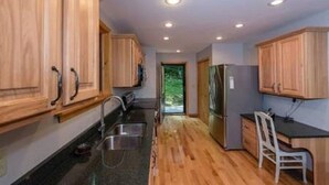 A kitchen with wooden cabinets, a stainless steel sink, and a refrigerator.