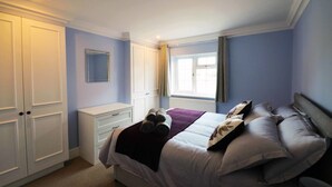 Une chambre à coucher avec un lit, une table de chevet, une armoire et une fenêtre.