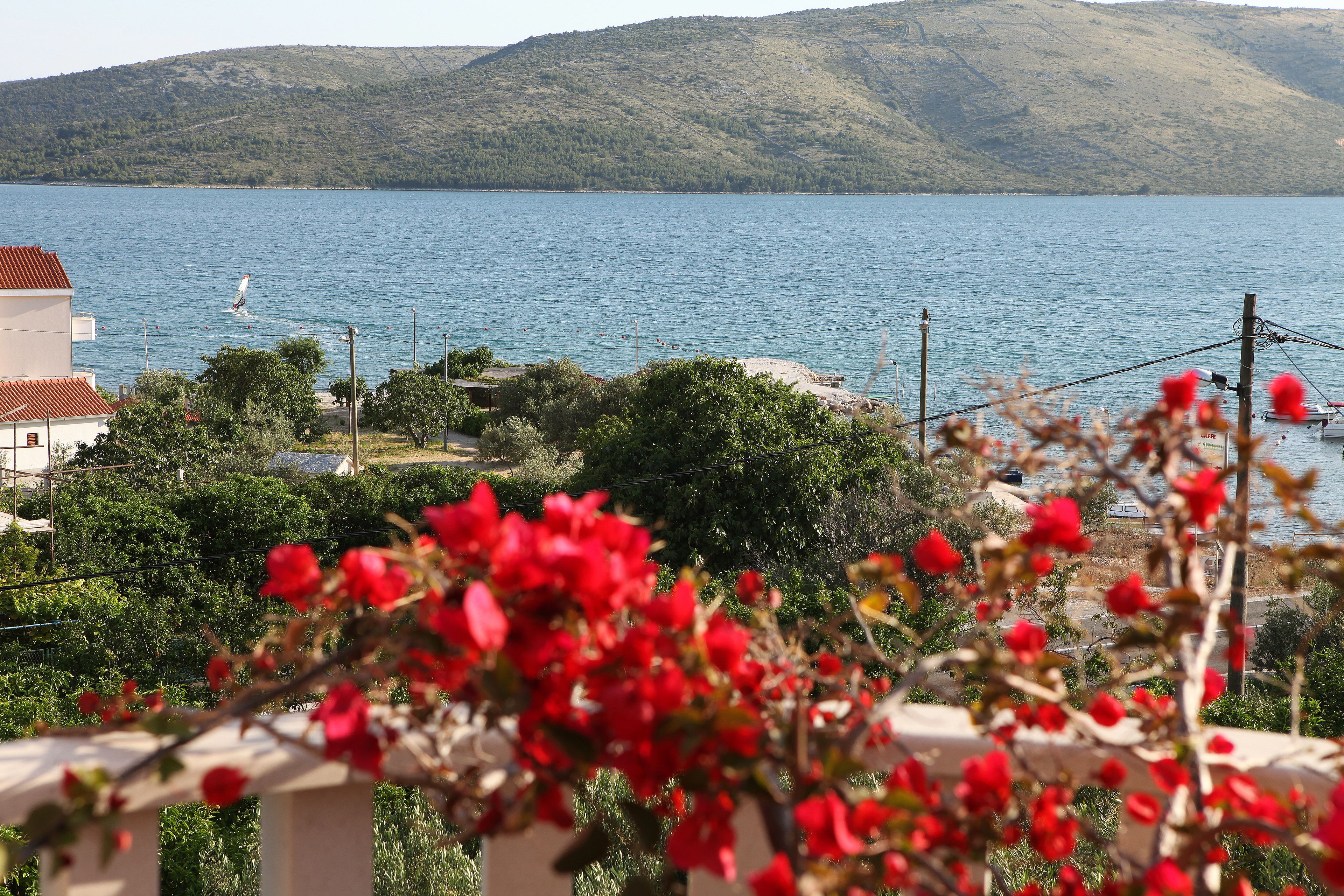 A coastal view with a body of water, greenery, and a building with a red roof.