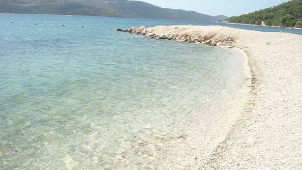 Una playa despejada con piedras y un litoral rocoso.