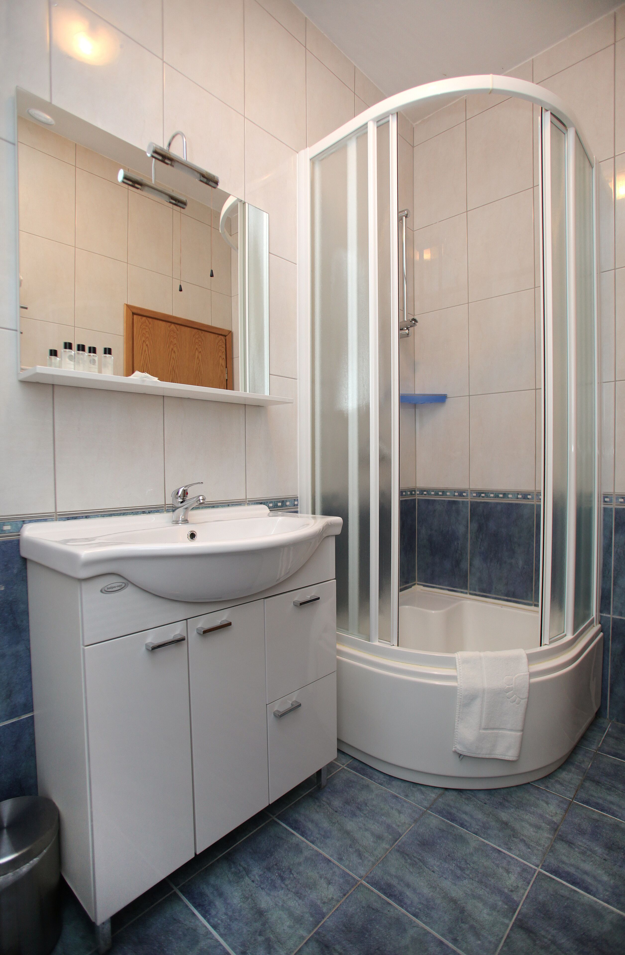 A bathroom with a white sink, mirror, and shower enclosure.