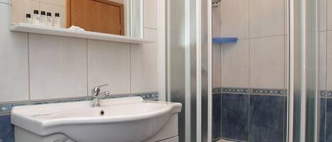 A bathroom with a white sink, mirror, and shower enclosure.