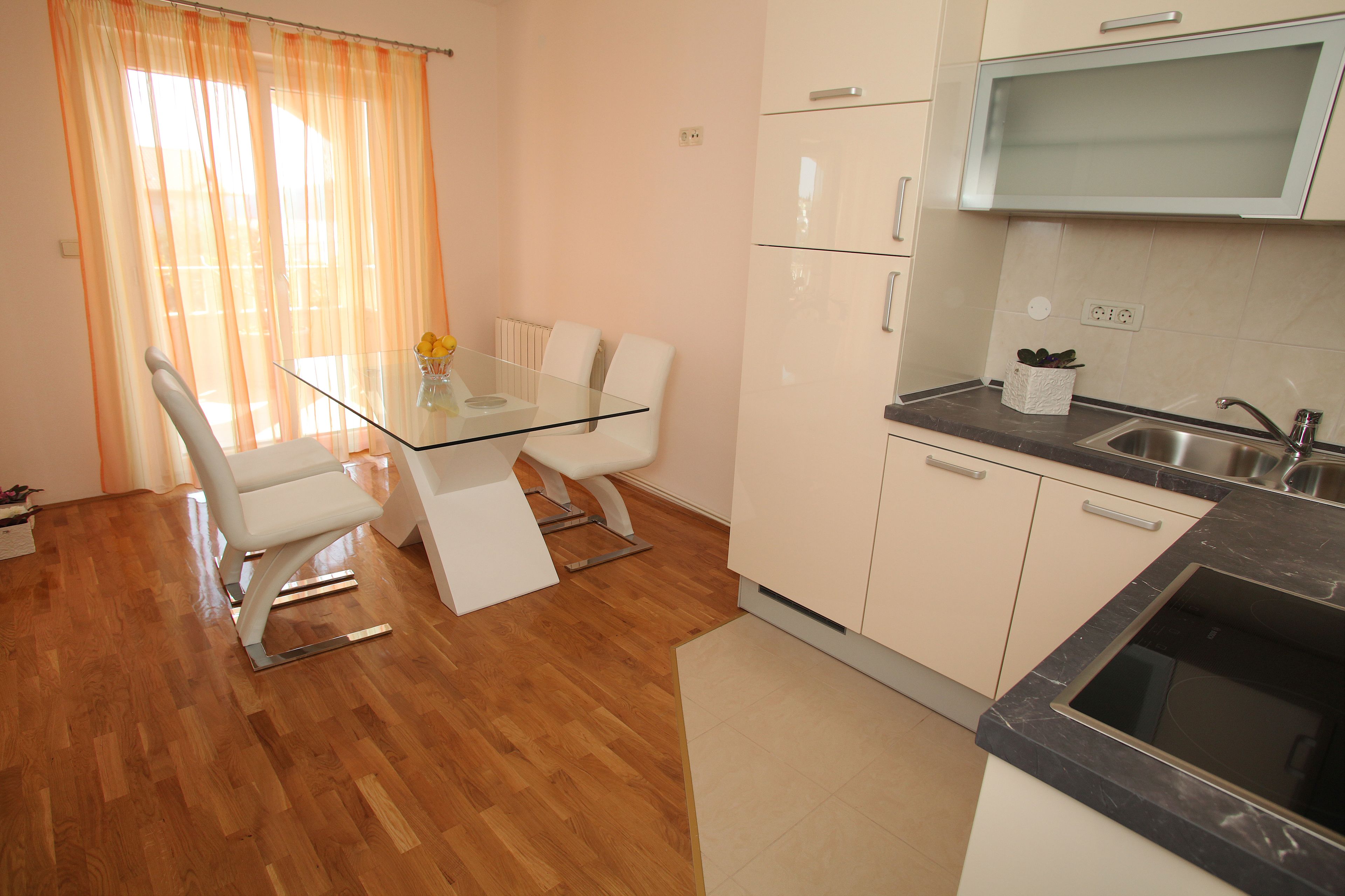 A modern kitchen with a built-in microwave, a sink, and a glass-top dining table with chairs.