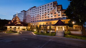 A multi-story hotel with a modern design, featuring a prominent entrance with a curved driveway and a decorative building in front.