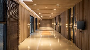 A modern hallway with wooden paneling, a polished floor, and recessed lighting. - The Heritage Chiang Rai Hotel and Convention (Chiang Rai)
